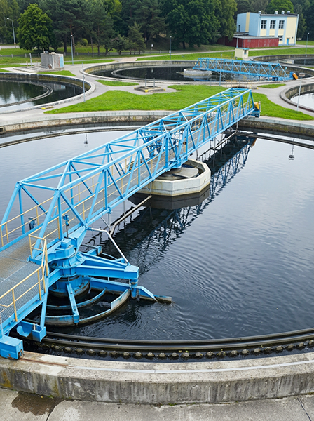 Blauwe roterende slibruimer in een rond bezinkbassin van een drinkwaterproductiebedrijf